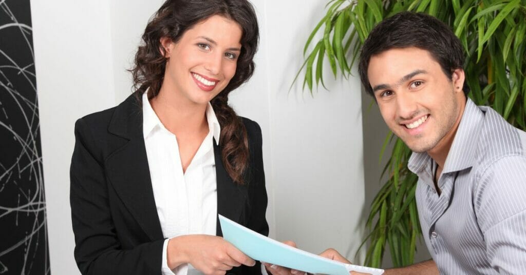 women handing papers to a man